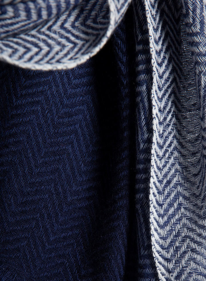 Close-up of a navy blue and white herringbone patterned fabric, showing the woven texture and folded edges.