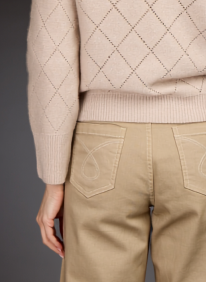 Close-up of a person wearing a light beige argyle knit sweater and tan pants, focusing on the back pockets and lower torso.